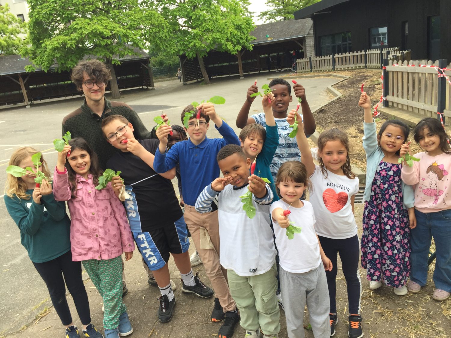 Groupe d'enfants avec un animateur jardin qui montrent des radis